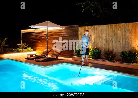 Mann, der den Swimmingpool mit einem Netz reinigt, entfernt Blätter und Wanzen Stockfoto