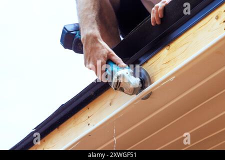 Zerlegung vorhandener Kunststoffpaneele aus Vinyl-Soffit auf eine bestimmte Größe an der Fassadendecke eines neuen Wohnhauses Stockfoto