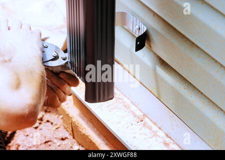 Arbeiter schneiden Aluminium-Regenrinne mit Metallschere. Stockfoto