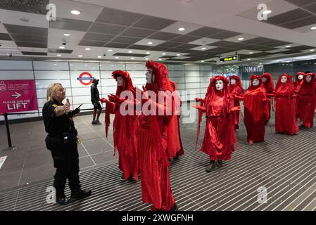 London, Großbritannien. August 2024. Die Red Rebel-Aktivistin MIME-Truppe von Extinction Rebellion tritt um den Bahnhof Euston herum auf, um gegen die Umweltauswirkungen des HS2-Eisenbahnprojekts, einschließlich des Verlusts von Bäumen und Grünflächen, zu protestieren. Das Projekt, dessen Zukunft ungewiss ist, hat das Budget enorm überschritten und in der Region massive Umwälzungen verursacht, darunter der Verlust von Häusern, Unternehmen und die Exhumierung von 50.000 menschlichen Überresten. Quelle: Ron Fassbender/Alamy Live News Stockfoto