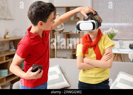 Kleiner Junge mit seinem Bruder, der zu Hause eine VR-Brille benutzt Stockfoto