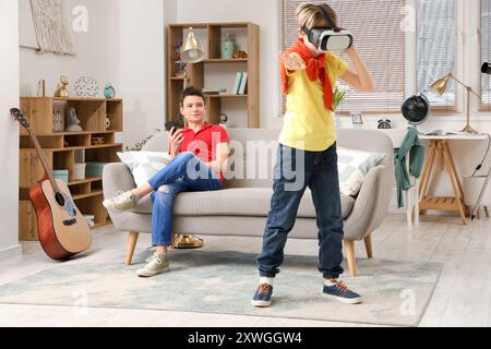 Kleiner Junge mit seinem Bruder, der zu Hause eine VR-Brille benutzt Stockfoto