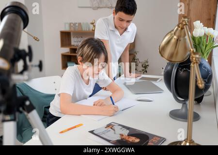 Kleiner Junge mit seinem älteren Bruder, der zu Hause Hausaufgaben macht Stockfoto