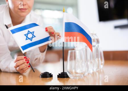 Ein nicht wiedererkennbares Mädchen setzt vor internationalen Verhandlungen Zwergflaggen von Russland und Israel Stockfoto