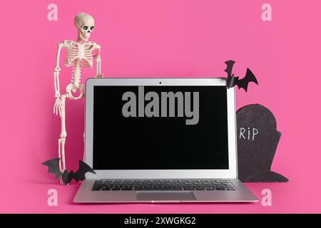 Moderner Laptop und Dekor für Halloween auf rosa Hintergrund Stockfoto