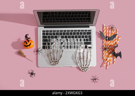 Komposition mit modernem Laptop und Dekor für Halloween auf rosa Hintergrund Stockfoto