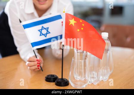 Ein nicht wiedererkennbares Mädchen setzt vor internationalen Verhandlungen Zwergenflaggen von China und Israel Stockfoto