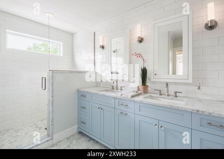 Weißes Badezimmer mit zwei Waschbecken in sanftem Blau und Duschkabine Stockfoto