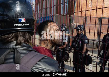 Chiago, USA. August 2024. Demonstranten schreien Polizisten in der Gegend zwischen den beiden Umzäunungen während eines Protestes in einem Park in der Nähe des United Center, wo die Demokratische Nationalkonvention stattfindet, in Chicago, IL am Montag, den 19. August 2024 an. Mindestens vier Personen wurden verhaftet, nachdem die Demonstranten einen der Umzäunungen durchbrochen hatten, die das Ereignis vor Demonstranten schützen sollten. Quelle: SIPA USA/Alamy Live News Stockfoto