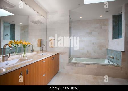 Modernes Hauptbadezimmer mit cremefarbenen Steinfliesen und langem Kirschtisch Stockfoto