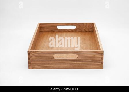 Massive Eschenholzschale mit Schwalbenschwanzfugen und seitlichen Aussparungen für einfaches Tragen auf weißem Hintergrund Stockfoto