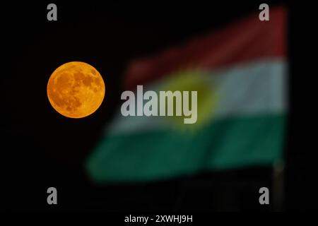 Duhok, Irak. August 2024. Der Supermond erhebt sich hinter der Flagge der Region Kurdistan am Himmel der nordirakischen Stadt Duhok. Quelle: SOPA Images Limited/Alamy Live News Stockfoto