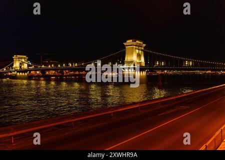 Budapest, Ungarn - 7. Juli 2024: Die Kettenbrücke in Budapest leuchtet bei Nacht auf und zeigt architektonische Schönheit. Stockfoto