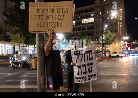 Ein Haredi-Jude hält ein Schild mit der Aufschrift „Shabbat Violator must sterben“, während er mit einem Gegenprotestoren während eines Solo-Protests gegen die Verletzung des jüdischen Samstages durch säkulare Juden am 19. August 2024 in Jerusalem steht. Stockfoto