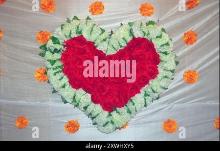 Herzsymbol aus roten und weißen Rosen auf weichem weißem Stoffhintergrund Stockfoto