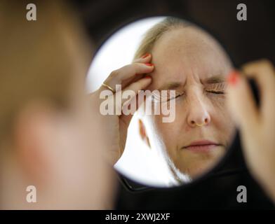 Symbolfoto zum Thema Migraene und Kopfschmerzen. Eine Frau reibt mit der Hand an ihrem schmerzenden Kopf. Berlin, 13.08.2024. Berlin Deutschland *** S Stockfoto