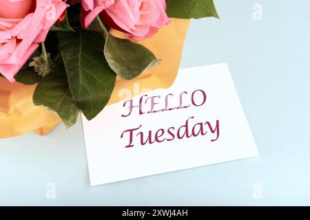 Die Worte HALLO DIENSTAG die Inschrift auf der Visitenkarte in der Komposition mit Blumen Stockfoto