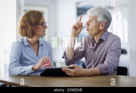 Symbolfoto. Eine Frau und ein Mann sitzt zusammen an einem Tisch mit einem Tablet und unterhält sich. Berlin, 13.08.2024. Berlin Deutschland *** Sy Stockfoto