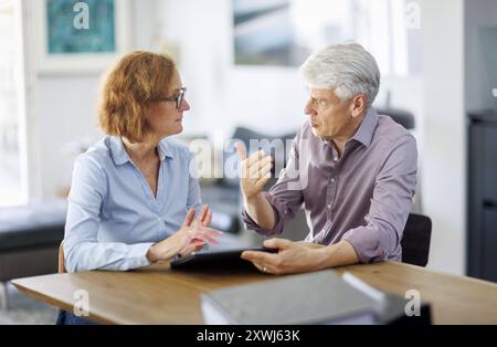 Symbolfoto. Eine Frau und ein Mann sitzt zusammen an einem Tisch mit einem Tablet und unterhält sich. Berlin, 13.08.2024. Berlin Deutschland *** Sy Stockfoto