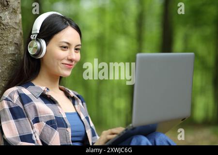 E-Learning für asiatische Frauen mit Laptop und Kopfhörer in einem Park Stockfoto