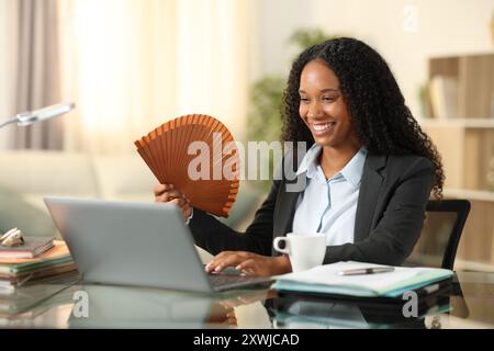 Glückliche schwarze Geschäftsfrau, die zu Hause mit einem Laptop arbeitet Stockfoto