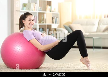 Profila einer schwangeren Frau schaut dich mit Fitnessball zu Hause an Stockfoto