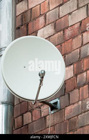 Antenne für Satellitenkommunikation an einer Ziegelwand Stockfoto