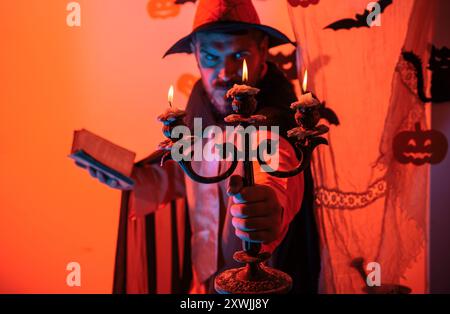 Mann auf dem Horror-Hintergrund. Halloween Hexe mit einem geschnitzten Kürbis und magischen Lichtern in einem dunklen Wald. Halloween-Party für glückliche Familie. Hexenhut Stockfoto