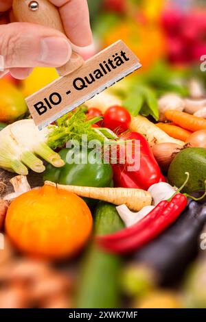 Bio-Qualität von Lebensmitteln ein Holzstempel ist beschriftet mit dem Aufdruck: Bio-Qualität über frisches Obst und Gemüse - FOTOMONTAGE *** Bio q Stockfoto