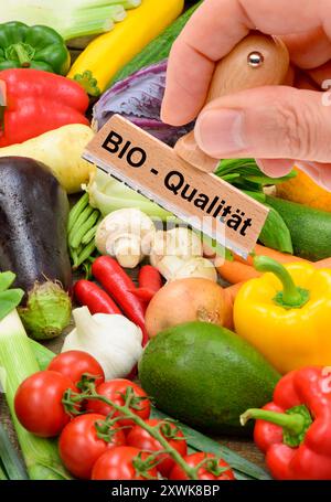 Bio-Qualität von Lebensmitteln ein Holzstempel ist beschriftet mit dem Aufdruck: Bio-Qualität über frisches Obst und Gemüse - FOTOMONTAGE *** Bio q Stockfoto