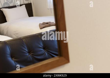 Hotelbett und Sofa spiegeln sich in einem Wandspiegel Stockfoto