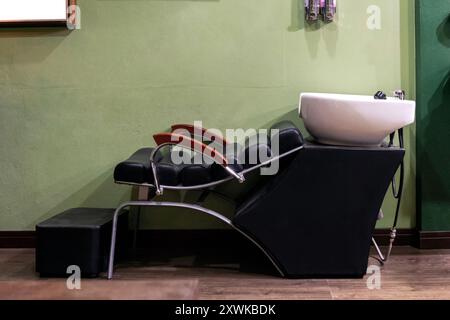 Ledersessel mit Keramik-Shampoo-Waschbecken im Friseur Stockfoto