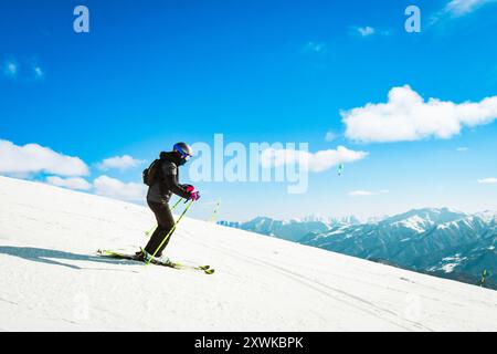 Dynamisches Bild einer Skifahrerin tragen schwarz isoliert auf der Piste Ski Downhill schnelle Bewegung in den Alpen. Aktive Winterferien, Skiabfahrten an bewölkten Tagen. Stockfoto
