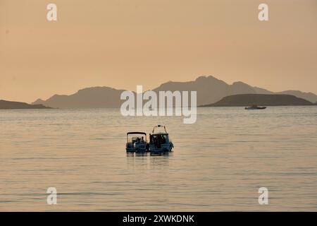 Während die Sonne über der Baiona Bay untergeht, schaffen Boote mit ihren Bugbögen, die auf die majestätischen Cies-Inseln zeigen, eine ruhige und malerische Szene. Das warme, gol Stockfoto