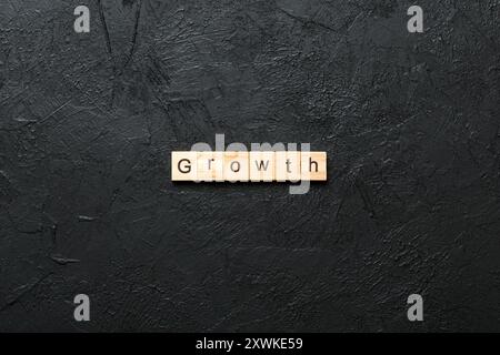 Wachstumswort auf Holzblock geschrieben. Wachstumstext auf dem Tisch, Konzept. Stockfoto