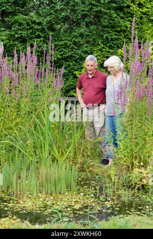Reifes älteres Ehepaar im Ruhestand, Mann und Frau, die gemeinsam Freude am Wildteich im Garten finden, glückliche Zweisamkeit Stockfoto