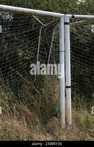 Überwachsene Fußballtorpfosten hohes Gras vernachlässigt zerrissene Netze Stockfoto