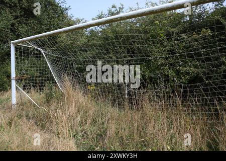 Überwachsene Fußballtorpfosten hohes Gras vernachlässigt zerrissene Netze Stockfoto