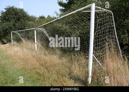 Überwachsene Fußballtorpfosten hohes Gras vernachlässigt zerrissene Netze Stockfoto