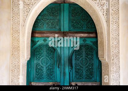 Verzierte türkisgrüne blaue marokkanische Bogentür Hintergrund, ornamental geschnitztes Holz, innen, der Turm am Le Jardin Secret, Marrakesch, Marokko Stockfoto