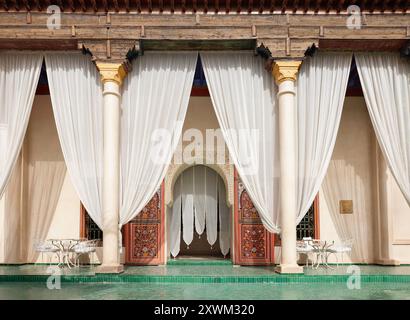 Eleganter Innenhof im Le Jardin Secret in Marrakesch mit grünen Mosaikfliesen, weißen Vorhängen, luxuriösem marokkanischem Design und traditioneller Architektur Stockfoto