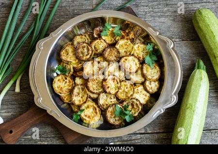 Gebratene Zucchini mit Petersilie im Teller auf rustikalem Hintergrund, vegetarische Speisen Stockfoto