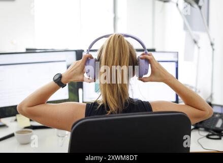 Eine Frau traegt Kopfhoerer in einem Buero in Berlin, 08.08.2024. Arbeit in einem Callcenter Berlin Deutschland *** Eine Frau trägt Kopfhörer in einem Off Stockfoto
