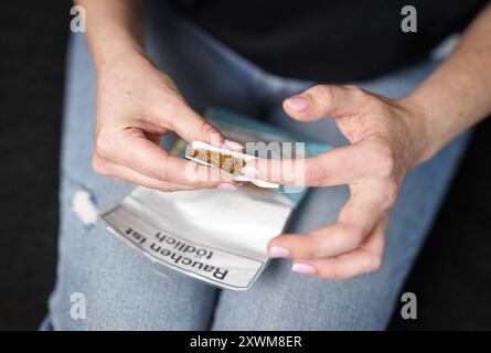 Eine Frau dreht sich eine Zigarette in Berlin, 08.08.2024. Berlin Deutschland *** Eine Frau, die in Berlin eine Zigarette rollt, 08 08 2024 Berlin Deutschland Polizist Stockfoto