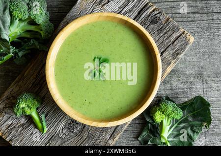 Frische Brokkoli-Suppe in Holzschüssel auf dunklem Tisch, Diät-Detox-Food-Konzept, Blick von oben Stockfoto