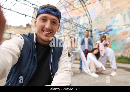 Mann macht Selfie mit einer Gruppe von Menschen im Freien, selektiver Fokus. Hip-Hop-Tänzer Stockfoto