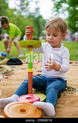 Kleines Mädchen, das mit Puzzlespiel spielt. Portraitbild eines 2-3 Kleinkindes. Glückliches Mädchen, das im Park das Plastikblöcke spielt. Stockfoto