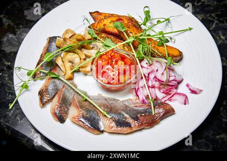 Hering mit gebackenen Kartoffeln, eingelegten Pilzen und süßen Zwiebeln Stockfoto