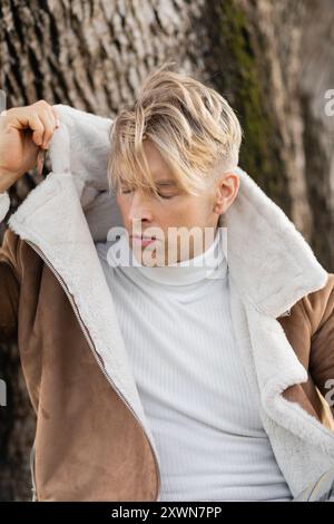 Ein hübscher blonder Mann in brauner Jacke und weißem Rollkragen Stockfoto