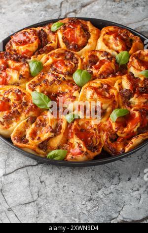 Italienische Pizzabötchen mit Tomaten, Käse, Würstchen und Basilikum in der Backform auf dem Tisch. Vertikal Stockfoto
